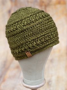 a green knitted hat sitting on top of a white mannequin head