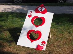 a white board with red hearts on it sitting in the grass next to a street