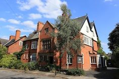 a large red brick building sitting on the side of a road next to trees and bushes