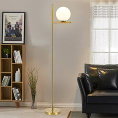 a living room with a black couch and a gold floor lamp in front of a window