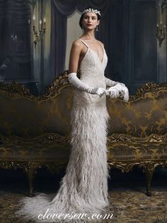 a woman standing in front of a couch wearing a white feathered dress and gloves