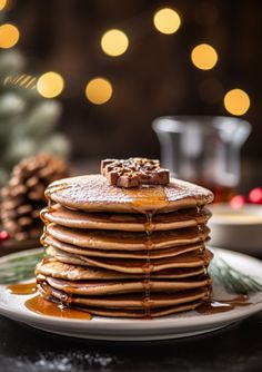 a stack of pancakes on a plate with syrup drizzled over them and pine cones in the background