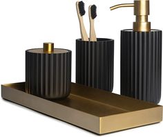 a black and gold bathroom set with toothbrushes and soap dispenser