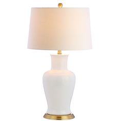 a white lamp with a gold base on a white background, it is dimmed by the light bulb