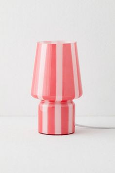 a pink and white striped lamp with a cord attached to the end, on a white surface