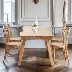 a wooden table and chairs in a room with white walls, wood floors and windows