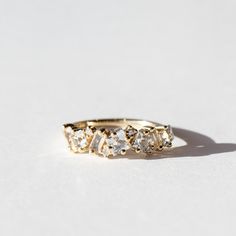 a gold ring with five stones on it sitting on a white surface, in front of the camera