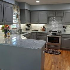 a kitchen with gray cabinets and wood floors