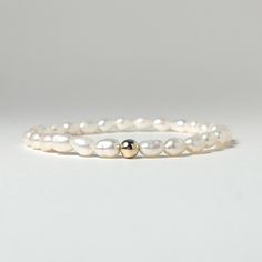 Why not start your stack with this dainty freshwater pearl bracelet?  Pair it with our gold filled beads or sterling silver to create a classic and timeless stack.   These dainty 4-6mm rice shaped freshwater pearls are genuine and natural and as such have irregular shapes.  This bracelet pretty to  wear alone or to stack with your metal or gemstones.  Each pearl bracelet has one metal bead. Choose gold or silver from dropdown. The stretch design provides a comfort fit and can stretch to fit a variety of wrist sizes.  Choose length in dropdown. MADE IN THE USA Everyday Stackable Pearl Bracelet, Dainty Stackable Pearl Bracelet, Classic Everyday Pearl Bracelet With 14k Gold Filled, Classic 14k Gold Filled Pearl Bracelet For Everyday, Classic 14k Gold Filled Pearl Bracelet, Classic Everyday 14k Gold-filled Pearl Bracelet, Classic Everyday Beaded Bracelets With Pearl Charm, Minimalist Pearl Bracelet With Round Beads, Classic White Pearl Bracelet With 14k Gold Fill