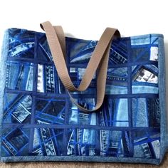 a handbag made out of fabric with blue squares on the front and bottom, sitting on a carpeted floor