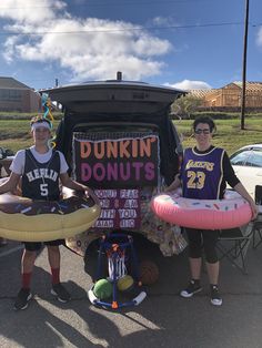 two women standing in front of a van with dunkin donuts