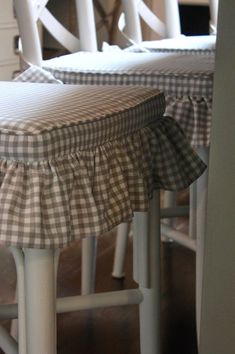 two white chairs with black and white gingham ruffled seat covers on them