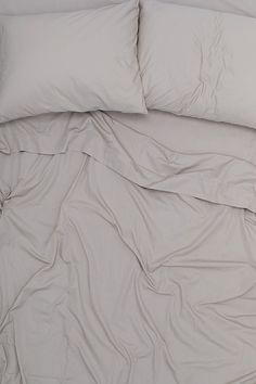 an unmade bed with white sheets and pillows