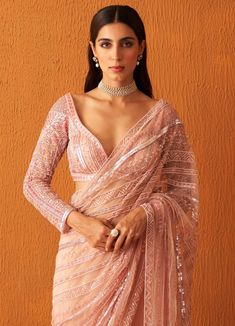 Featuring a rose pink embellished net saree with sequins, pearls and crystals work all over. Paired with a sweetheart deep neckline full sleeved blouse with sequins and pearl embellishments in set pattern along with the tassel tie-up at the back. Composition : Saree: Net, Blouse: Georgette Care: Dry Clean Only and Vacuum Storage All products can be customised for sleeves, length of blouse and neck design Delivery : 4-6 weeks as the product is hand crafted. Check Size Guide or choose MySize for free customisation (All Sizes above XL can be made at 15% additional cost) For more information and sizes please contact fabiliciousfashion@gmail.com or visit our Copenhagen studio.About the Designer : Angad Singh's journey in the world of fashion started with at an early age as he grew up in a famil Festive Glamorous Blouse With Sheer Dupatta, Glamorous Festive Blouse With Sheer Dupatta, Pink Party Wear Pre-draped Saree With Sequins, Diwali Bollywood Style Hand Embellished Blouse, Pink Sequined Pre-draped Saree For Party, Glamorous Pink Pre-draped Saree For Festive Occasion, Diwali Bollywood Hand Embellished Blouse, Glamorous Pink Blouse Piece For Parties, Glamorous V-neck Blouse For Wedding