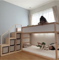 a child laying on top of a bunk bed in a room with wooden floors and stairs