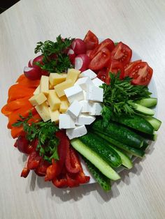 a platter filled with vegetables and cheese on top of a table