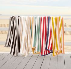 towels hanging on a clothes line with the ocean in the backgroung behind them