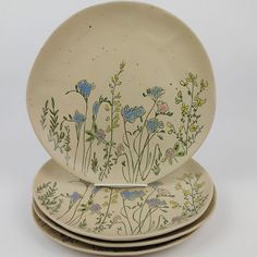 three plates with flowers painted on them stacked up next to each other in front of a white background