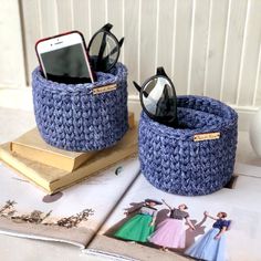 there are two blue baskets on the table with books and cell phones in them,