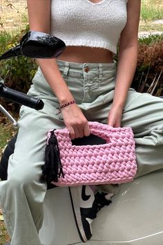 a woman sitting on a scooter holding a pink purse