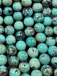 turquoise green and brown speckled beads are stacked on top of each other in rows