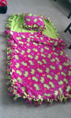 a pink and green blanket laying on the floor