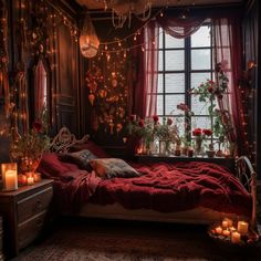 a bedroom decorated in red and gold with candles on the bed, windows, and curtains