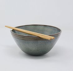 two bowls with chopsticks in them on a white surface, one is green and the other is brown