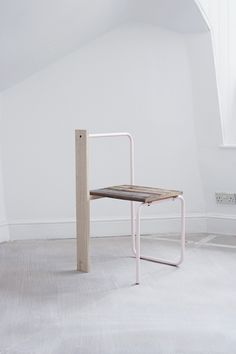 a chair sitting on top of a white floor next to a wooden table in an empty room