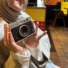 a woman wearing a hijab holding an old camera