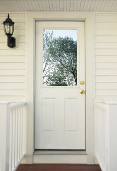 a white front door with a light on the side and a lantern hanging above it