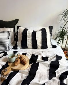 a bed with black and white striped comforter next to a wooden cutting board on top of it