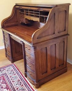 an old wooden desk with drawers and a rug on the floor in front of it