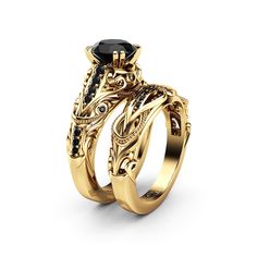 two gold wedding rings with black diamonds on each side and an intricate design in the middle