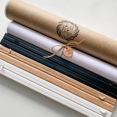 a stack of different colored papers on top of each other with a brown ribbon tied around them