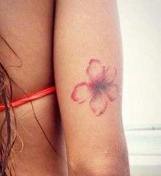 a close up of a person with a flower tattoo on her arm and behind her back