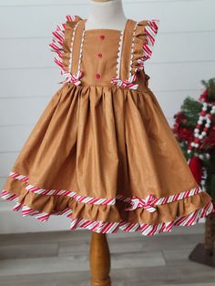 Girls Gingerbread Dress Adorable girls Gingerbread Dress! Features fun trim and ties in back. Gingerbread Christmas Dress, Fitted Holiday Dress With Ruffles For Winter, Fitted Ruffle Holiday Dress For Dress-up Events, Fitted Ruffle Holiday Dress For Dress-up, Formal Fitted Ruffle Holiday Dress, Fitted Christmas Holiday Dress With Ruffles, Fitted Christmas Dress With Ruffles, Fitted Holiday Dress With Ruffles For Christmas, Fitted Sleeveless Christmas Holiday Dress