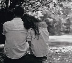 black and white photograph of two people sitting on the ground in the rain looking at trees