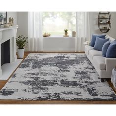 a living room with a couch, chair and rug in grey and white colors on the floor