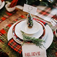 a christmas table setting with place settings, napkins and small trees on the plates