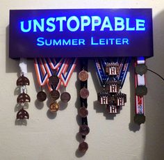 a sign that says unstoppable summer letter with medals hanging from it's sides