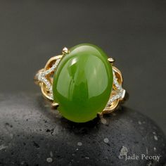 A statement piece that is bound to bring a vibrant and energetically enhanced essence to your days, this Statement Nephrite Jade Ring is both classic and contemporary. The center stone is a natural, untreated AAA nephrite jade stone of a statement-sized 11.75 carats, set in a four prong setting. With intricate details featuring 0.07 carats of sparking white diamonds on either side of the stone, this piece is set in a warm 18kt rose gold setting. Dimensions: Center Stone: Natural, untreated AAA N Elegant Large Stone Green Emerald Ring, Elegant Green Emerald Ring With Large Stone, Elegant Large Green Emerald Ring, Elegant Green Ring With Large Stone, Elegant Green Rings With Large Stone, 35th Wedding Anniversary, Chinese Jade, Nephrite Jade, Jade Ring