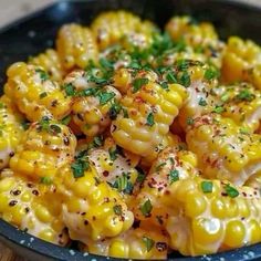 corn on the cob with herbs and seasoning in a black bowl, ready to be eaten