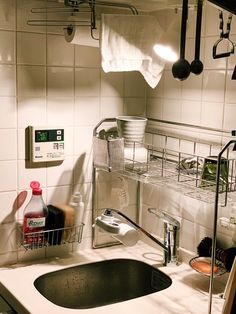 a kitchen sink with dishes and utensils hanging from the wall above it,