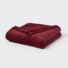 a blanket that is laying on top of a white surface with a dark red color