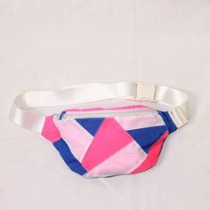 a pink, blue and white fanny bag on a white surface with a belt around the waist