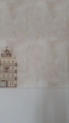 a toy house sitting on top of a white shelf in front of a beige wall