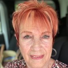 an older woman with red hair smiling at the camera