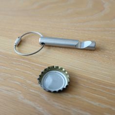 a bottle opener sitting on top of a wooden table next to a metal bottle cap