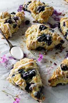 scones with blueberries and white chocolate drizzled on them, next to a spoon